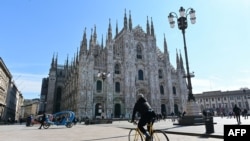 A biker rides past the Duomo di Milano on Piazza del Duomo in central Milan on March 8, 2020.