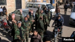 Fighters loyal to Syria's President Bashar al-Assad celebrate with residents of Nubul and al-Zahraa after breaking the siege of their towns in the northern Aleppo countryside, Syria, in this handout picture provided by SANA, Feb. 4, 2016.