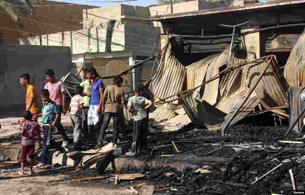 Children look at the site of a bomb attack, one day after the blast, in the center of Baquba, northeast of Baghdad, August 15, 2013.