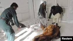 Afghan policemen carry the dead body of a victim at a local hospital after a suicide bomb attack in Khost province, December 26, 2012.