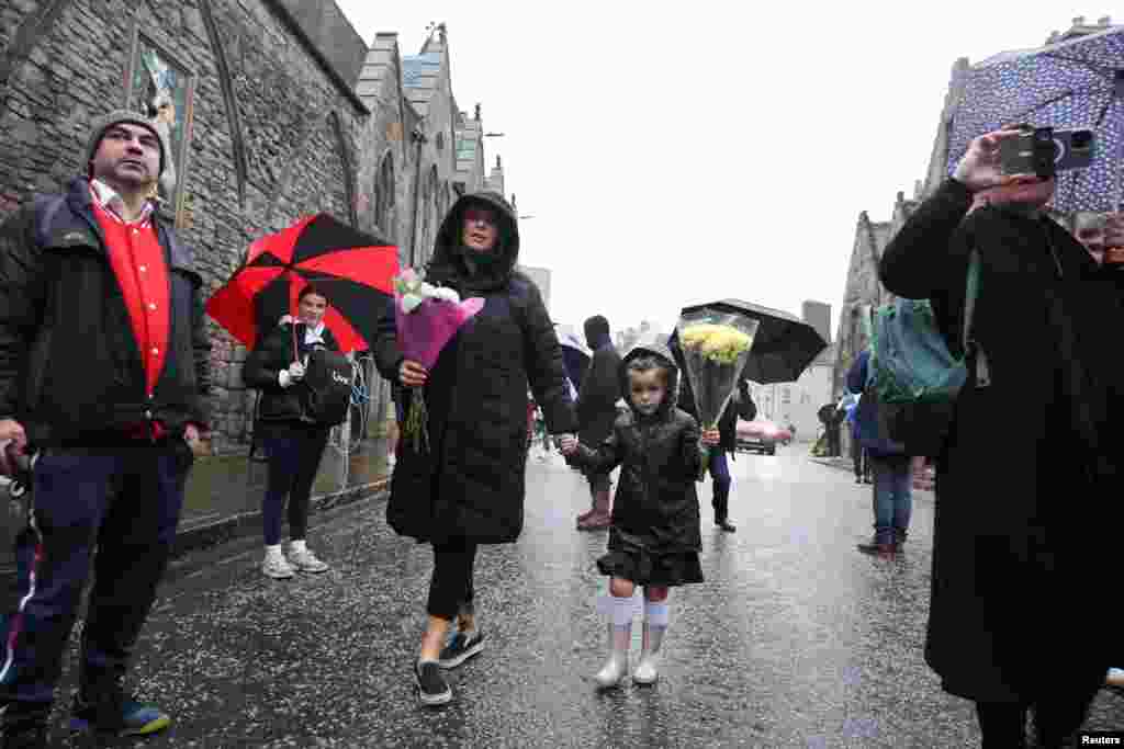 People carry flowers near the Palace of Holyroodhouse, after the announcement Queen Elizabeth's death, Sept. 8, 2022.
