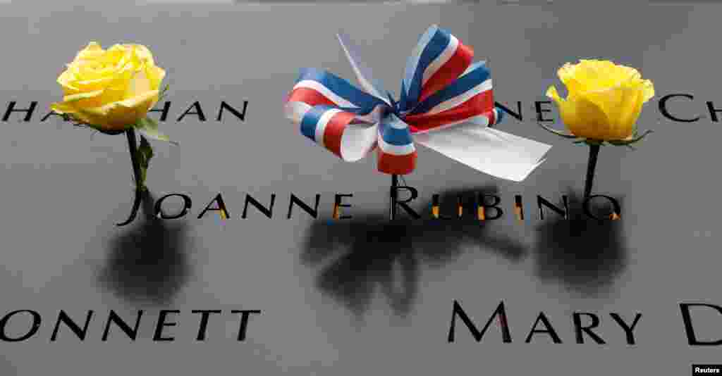 A ribbon and roses are placed on one of the victims' name at the north reflecting pool of the National 9/11 Memorial in New York, Sept. 11, 2018.