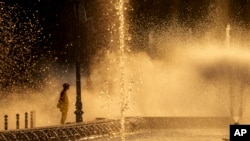 A municipal worker cools off next to a city fountain in Bucharest, Romania, July 11, 2024, as temperatures exceeded 39 degrees Celsius.