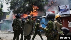 Polisi wa kutuliza ghasia wakiwa jirani na majengo ya biashara zilizoteketeza moto wakati wa maandamano huko Kisumu Julai 12, 2023. Picha na REUTERS/James Keyi. 
