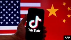 Logo TikTok terlihat di layar iPhone di depan bendera AS dan China di Washington, DC dalam sebuah ilustrasi yang diambil pada 16 Maret 2023.