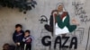 Displaced Palestinian children stand next to a mural painting by artist Amal Abo in Rafah in the southern of Gaza Strip, Dec. 31, 2023.