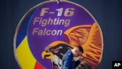 A Romanian serviceman walks by a logo on a hangar door at the Baza 86 military air base, outside Fetesti, Romania, Nov. 13, 2023. 
