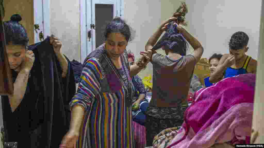 Waffa, a single mother who lives with over a dozen family members, including nine children, combs her daughter Mariam’s hair as her nephews dress up in their new Eid outfits from a local charity.