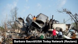 KeUntey Ousley intenta salvar lo que puede del vehículo del novio de su madre, mientras su madre LaShata Ousley y su novia Mikita Davis observan, después de que un tornado atravesara su pequeña ciudad de Delta la noche anterior en Rolling Fork, Mississippi, EEUU, el 25 de marzo de 2023.