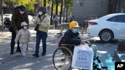 北京一家兒童醫院外一名坐在輪椅上的男孩手拿醫院影像科的片子。（2023年11月24日）