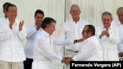 ARCHIVO - El entonces presidente de Colombia, Juan Manuel Santos, (izq), saluda al comandante de las extintas Fuerzas Armadas Revolucionarias de Colombia, FARC, Rodrigo Londoño, alias Timochenko, (der) se dan la mano después de firmar la paz, el 26 de septiembre de 2016. 