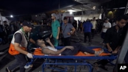 A wounded Palestinian is carried into the al-Shifa hospital following Israeli airstrikes on Gaza City, Oct. 26, 2023.