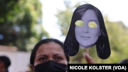 Una mujer sostiene un recorte de papel con una máscara con el rostro de Rocío San Miguel, durante una manifestación frente a la embajada de España para exigir su liberación. Caracas, 20 de febrero 2024