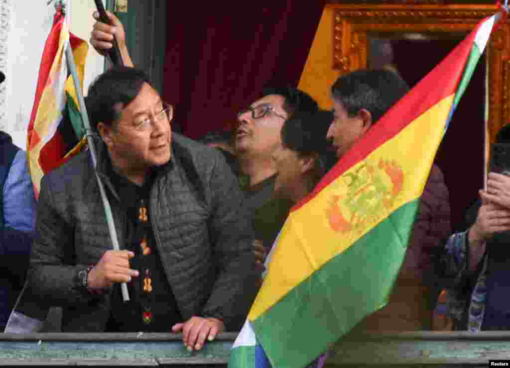 Bolivia's President Luis Arce holds a flag as he stands on a balcony after he "denounced the irregular mobilization" of some units of the country's army in La Paz, June 26, 2024.
