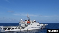 资料照:2024年2月8日,菲律宾南中国海斯卡伯勒浅滩附近,一艘中国海岸警卫队船只在菲律宾海岸警卫队船只特雷莎·马格巴努亚号旁驶过。(路透社)