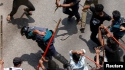 Seorang polisi dipukuli oleh massa saat bentrokan antara para pendukung antikuota, polisi dan pendukung Liga Awami di wilayah Rampura, di Dhaka, Bangladesh, Kamis, 18 Juli 2024. (Foto: Mohammad Ponir Hossain/Reuters)