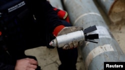 FILE - A Ukrainian military serviceman holds a defused cluster bomb among a display of pieces of Russian army rockets that a Ukrainian munitions expert said did not explode on impact, in Kharkiv region, Ukraine, Oct. 21, 2022. 
