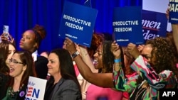 Sejumlah perempuan memegang spanduk sambil mendengarkan Wakil Presiden Kamala Harris berbicara tentang kebebasan reproduksi di El Rio Neighborhood Center, Tucson, Arizona, pada 12 April 2024. (Foto: AFP)