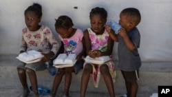 ARCHIVO: Niños en albergues para personas desplazadas por la violencia de las pandillas reciben raciones de alimentos en el vecindario de Tabarre de Puerto Príncipe, Haití, el 19 de mayo de 2024.