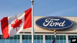FILE - Bendera Kanada berkibar tertiup angin di dekat logo Ford di kantor pusat pembuat mobil tersebut di Dearborn, Michigan, 26 Oktober 2009.