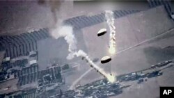 Foto dari tangkapan layar oleh Angkatan Udara AS tampak suar-suar yang dipasang di parasut melayang di udara. Suar-suar itu menurut AU AS dilepaskan oleh jet Rusia, SU-35, di atas wilayah udara Suriah, Rabu, 5 Juli 2023. (Foto: U.S. Air Force via AP)