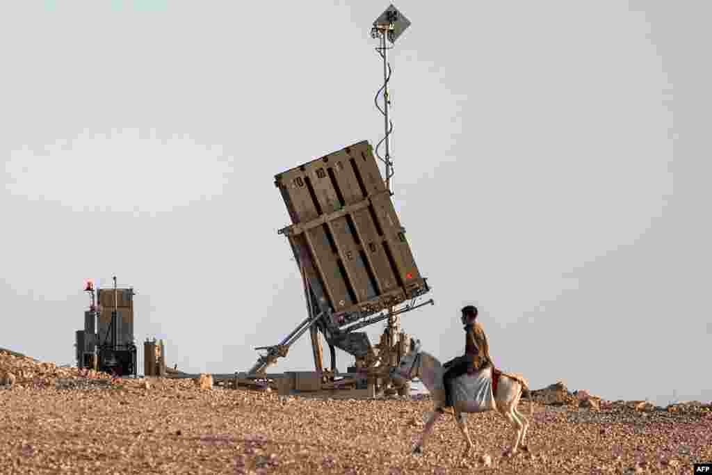 A boy rides a donkey near one of the batteries of Israel's Iron Dome missile defense system at a village not recognized by Israeli authorities in the southern Negev desert.