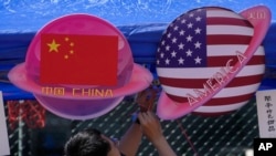 FILE - A vendor sets up foods and beverages at a booth displaying planets shaped of China and American flags during a Spring Carnival in Beijing on May 13, 2023.