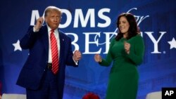 El presidente Donald Trump junto a la cofundadora de Moms for Liberty, Tiffany Justice durante su ingreso al encuentro anual de la organización.