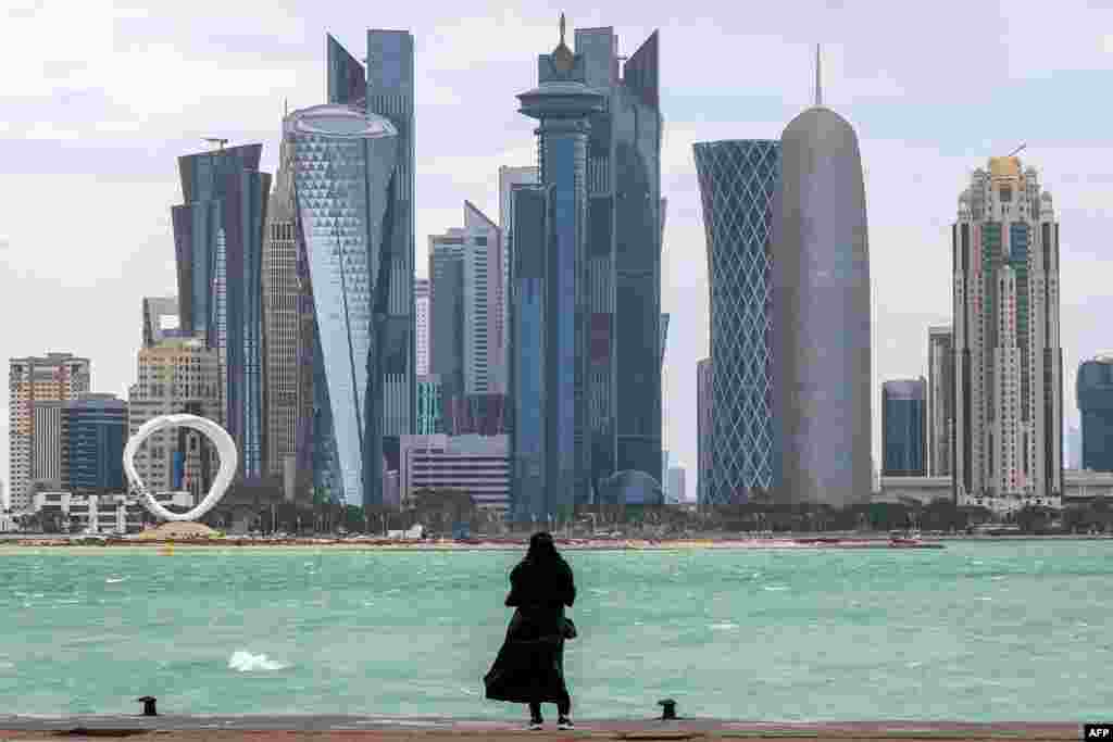 A woman stands by the waterfront at the Doha corniche facing the high-rise buildings in the West Bay district.