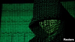 FILE - Binary code is projected onto a hooded man in this illustration photo taken on May 13, 2017. (TPX Images via Reuters)