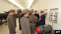 김정은(오른쪽) 북한 국무위원장이 지난달 27일 600mm 초대형방사포와 순항미사일 화살-1형·화살-2형, 단거리탄도미사일 화성-11형 등에 탑재 가능한 전술 핵탄두 '화산-31'을 살펴봤다며 관영매체가 다음날 공개한 장면. (자료사진)