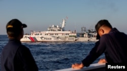 菲律賓海岸警衛隊的成員注視著中國海警船在南中國海攔截他們駛往第二托馬斯淺灘海域供給船。 （2024年3月5日）