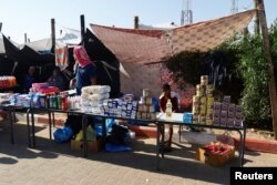 Seorang anak laki-laki Palestina duduk di dekat bantuan pangan di dekat tenda sebuah kamp yang dikelola PBB di Khan Younis, selatan Jalur Gaza, 26 Oktober 2023. (REUTERS/Ibraheem Abu Mustafa)
