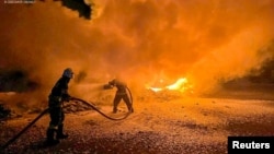 Firefighters extinguish burning trucks damaged during a Russian drone attack at a port on Danube river in Odesa region, Ukraine, Sept. 26, 2023. (State Emergency Service of Ukraine, via Reuters)