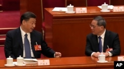 中國國家主席習近平2023年3月12日在全國人民代表大會上與中國總理李強交談。