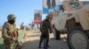FILE - Ugandan peacekeepers with the African Union Transition Mission in Somalia (ATMIS) stand next to their armored vehicle on a street in Mogadishu, Somalia, May 10, 2022.