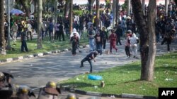Para pengunjuk rasa melempar batu ke arah polisi dalam demonstrasi menentang rencana pengembangan Pulau Rempang yang didanai China, 11 September 2023. Rencana itu diperkirakan akan menggusur 7.500 warga. (Foto: Andaru/AFP)