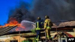 FILE - Petugas pemadam kebakaran memadamkan api di gudang setelah serangan di Kherson, 19 September 2023. (Foto AFP / Selebaran / Layanan Darurat Ukraina)