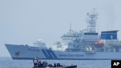 Boti ya walinzi wa bahari wa Ufilipino ikipita mbele ya meli ya walinzi wa Japan, kwenye maji ya bahari ya South China Sea.