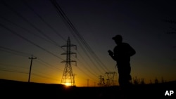 A jogger passes under power lines during an evening run, June 26, 2023, in San Antonio. Meteorologists say scorching temperatures brought on by a heat dome threaten to bring record highs to the state.