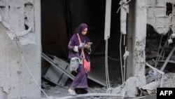 Una mujer revisa su teléfono mientras está de pie entre los escombros de un edificio destruido durante un bombardeo israelí en el barrio Sheikh Radwan de la ciudad de Gaza, el 11 de agosto de 2024.