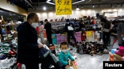 ARCHIVO - Clientes compran en una zapatería durante una venta de liquidación en un centro comercial en Beijing, China, el 15 de enero de 2023.