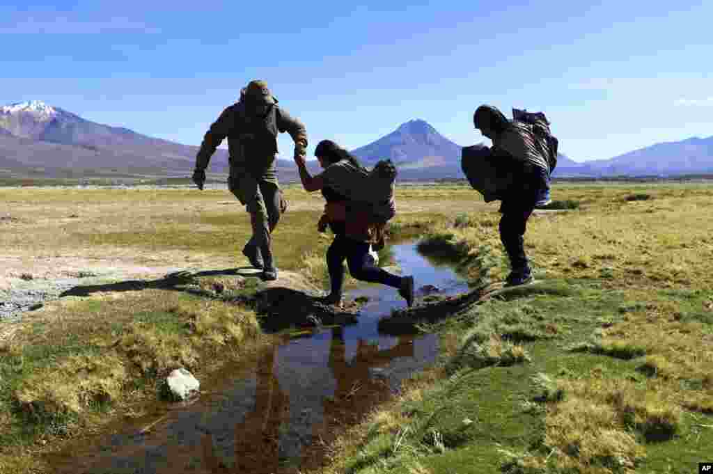 A Chilean soldier helps a migrant cross a water canal near Colchane before the migrants are taken to a shelter for registration. The government announced it's increasing military presence on its border with Peru and Bolivia to tackle illegal immigration.