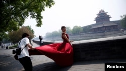 一名攝影師在北京故宮角樓外為一名紅衣女子拍攝婚紗照。（2020年5月1日）