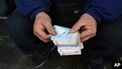 FILE - A street money exchanger counts Iranian banknotes at a commercial district in downtown Tehran, Dec. 23, 2022. 