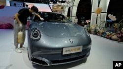 Seorang pekerja membersihkan Ora, sebuah mobil listrik China, selama Auto Shanghai 2023 di sebuah pusat konvensi di Shanghai, 18 April 2023. (Foto: AP)