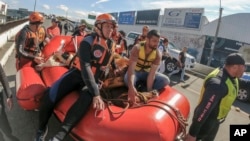 Firefighters use a raft to transport a horse after rescuing it from a roof, where it was trapped for days amid flooding, after heavy rain in Canoas, Rio Grande do Sul state, Brazil, May 9, 2024. 