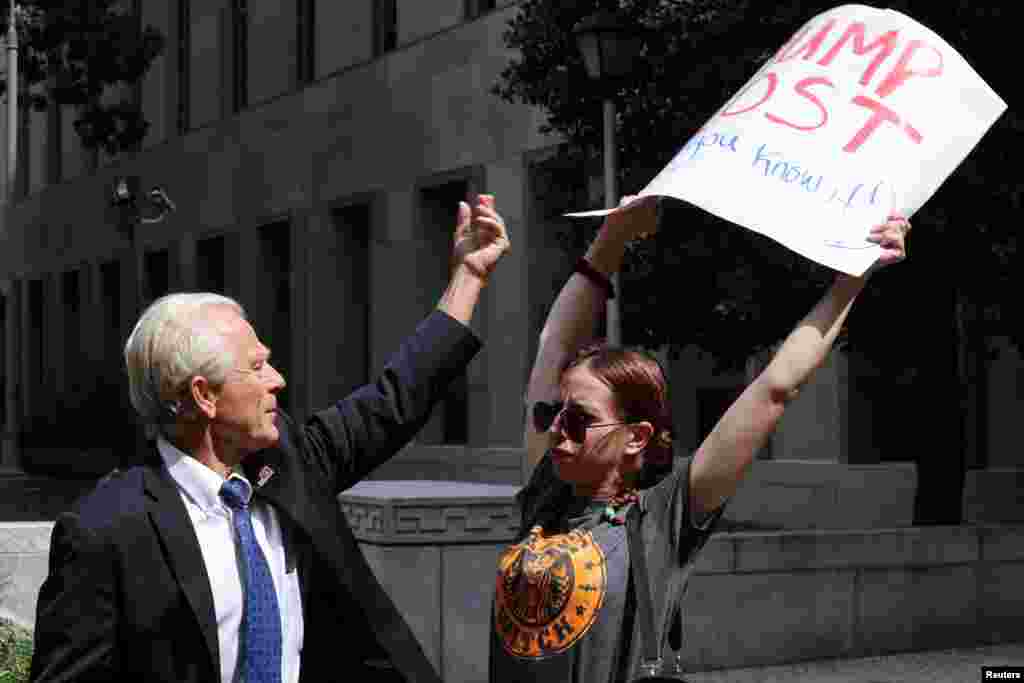Peter Navarro, a White House economic adviser under former U.S. President Donald Trump, tries to grab a protester's sign while speaking to reporters after a pre-trial conference in an attempt to get contempt of Congress charges against him dismissed, at U.S. District Court in Washington.