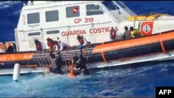  Walinzi wa pwani ya Italia wakiwasaidia wahamiaji kuingia katika boti baada ya kuwaokoa wahamiaji katika operesheni maalum kusini mwa Lampedusa, Picha ilitolewa Aug. 6, 2023, (Picha na Italian Coastguard / Guardia Costiera / AFP) 