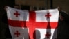 Activists hold a Georgian flag at a rally outside a parliament building during a plenary session of parliament on the controversial "foreign agents" bill, that sparked mass protests in recent days, in Tbilisi, Georgia, March 10, 2023.